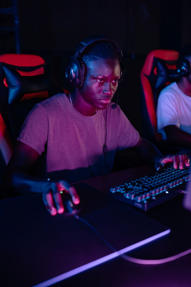 Focused gamer wearing headset immersed in competitive PC gaming at night.