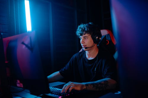 A Tattooed Man in a Black Shirt Gaming on a Desktop