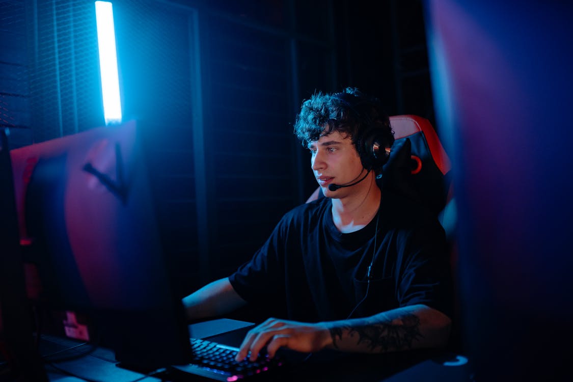 A Tattooed Man in a Black Shirt Gaming on a Desktop