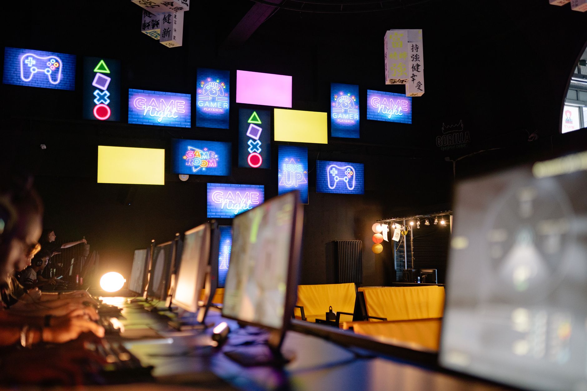 Illuminated gaming room with colorful screens and neon signs, creating an immersive gaming experience.
