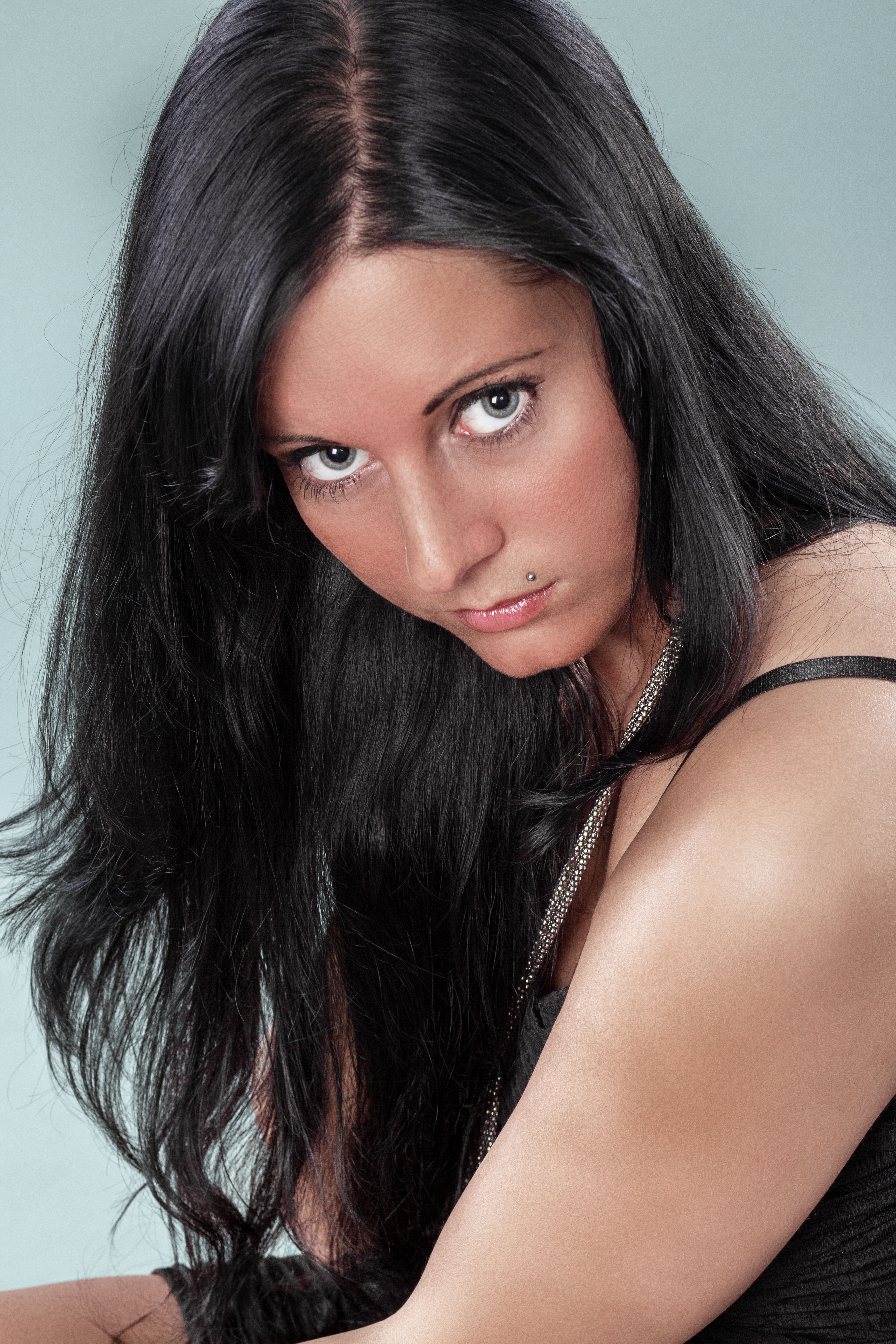Close-up portrait of a woman with long black hair posing with an intense gaze.