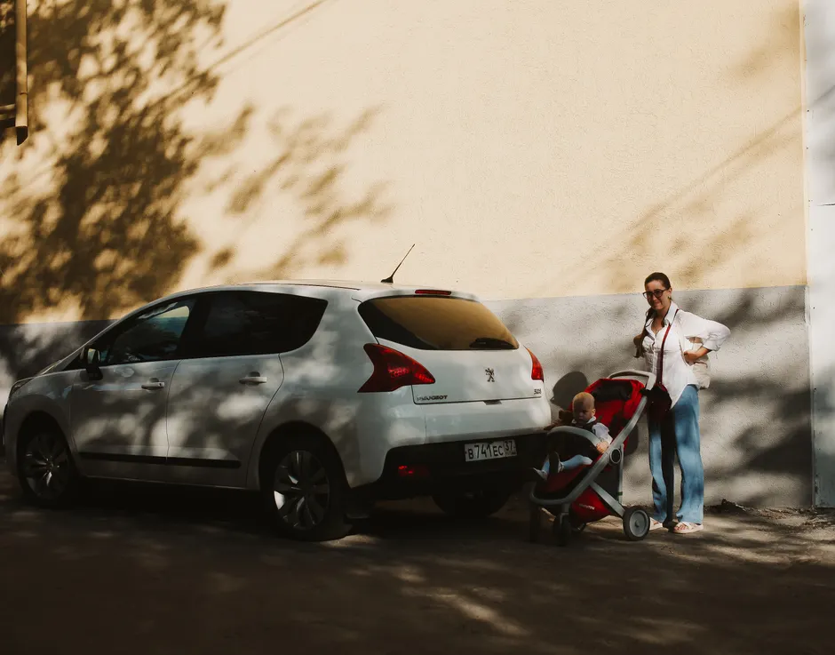 Parent chargeant une poussette pliée dans le coffre d’une voiture