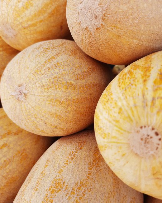 Fresh, ripe cantaloupes stacked in a detailed close-up shot.