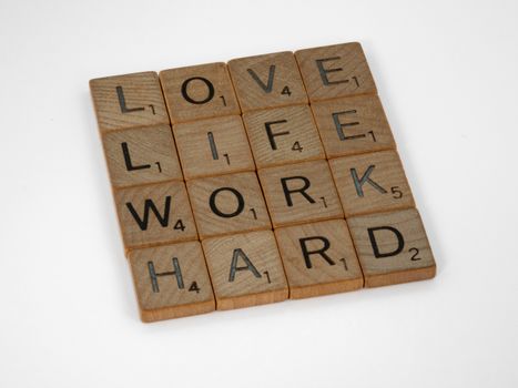 Scrabble tiles spelling 'Love Life Work Hard' on a white background, conveying motivation.