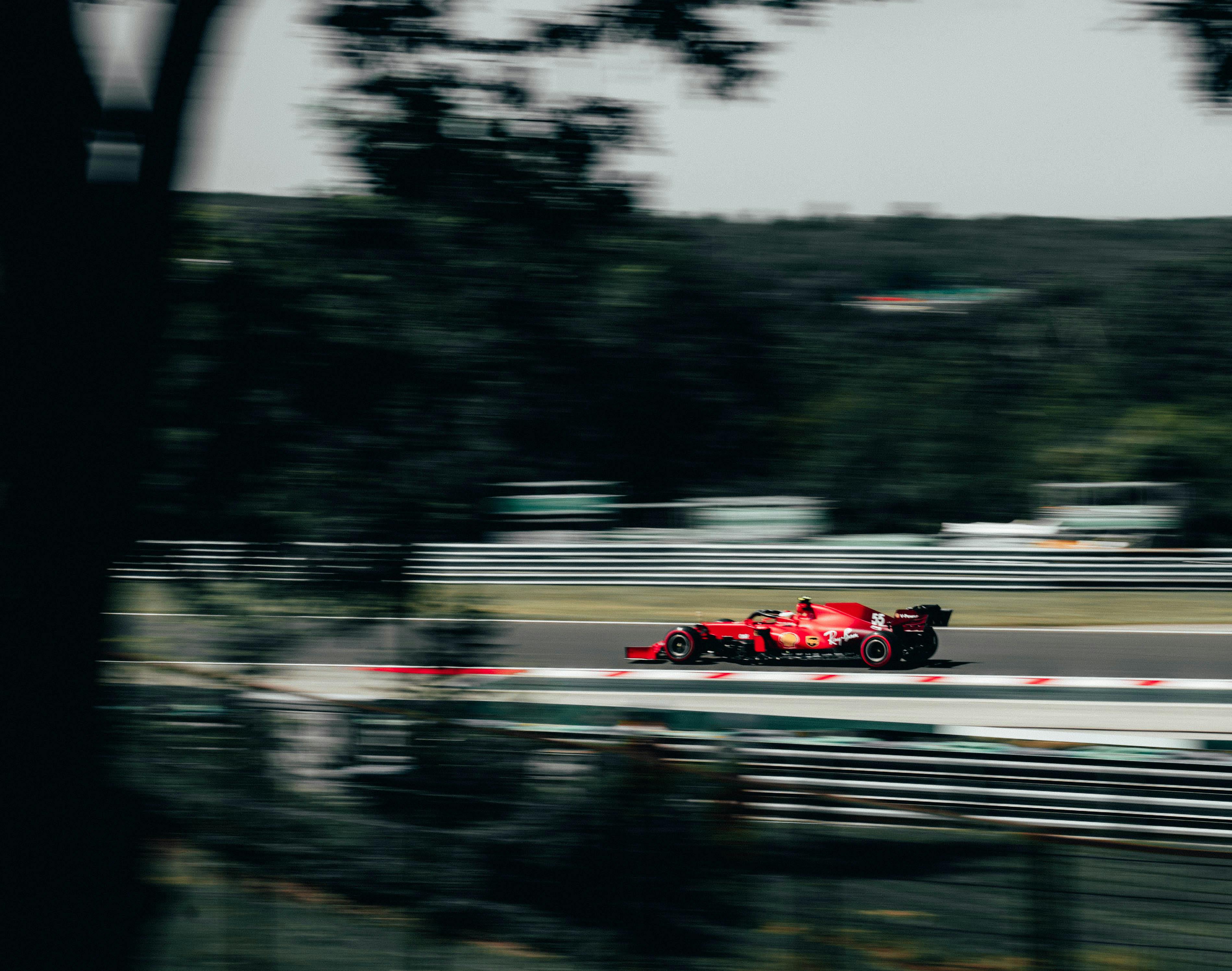 Red racing car speeds on the Hungaroring track, capturing the thrill of motorsport.