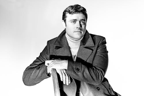 Man Wearing a Coat Sitting on Chair