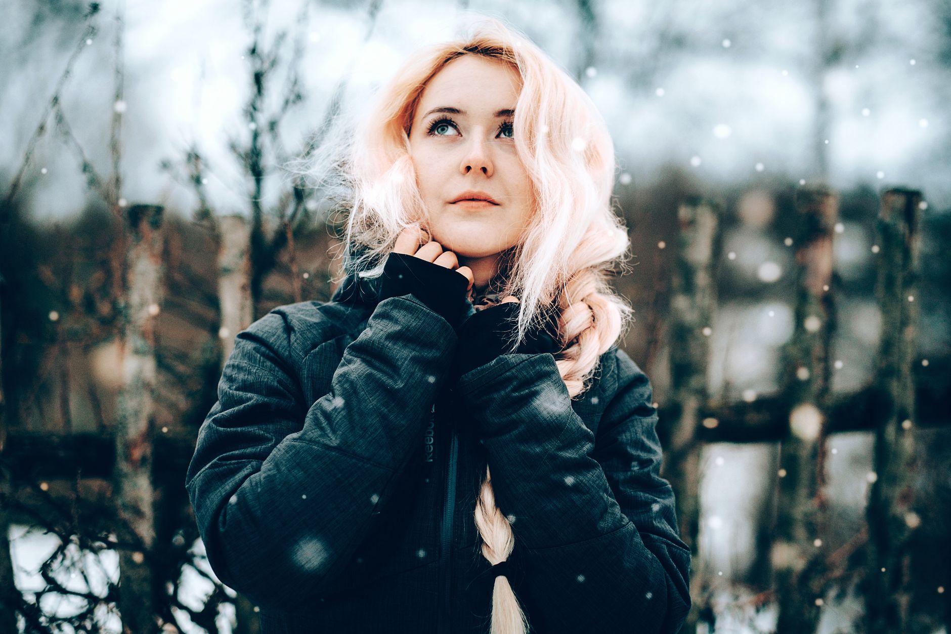 Portrait of a young blonde woman in a black jacket enjoying a snowy winter day outdoors.