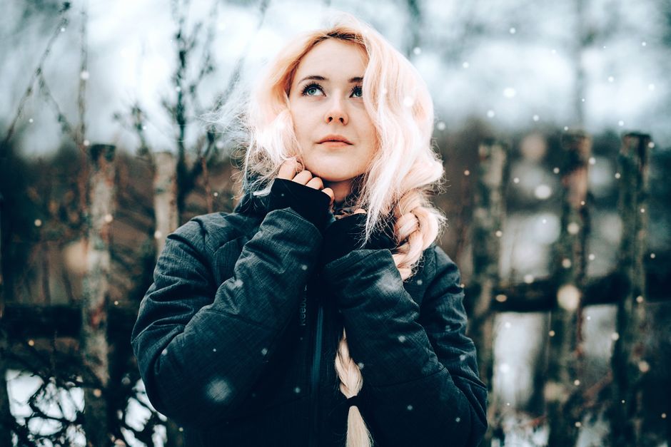Portrait of a young blonde woman in a black jacket enjoying a snowy winter day outdoors.