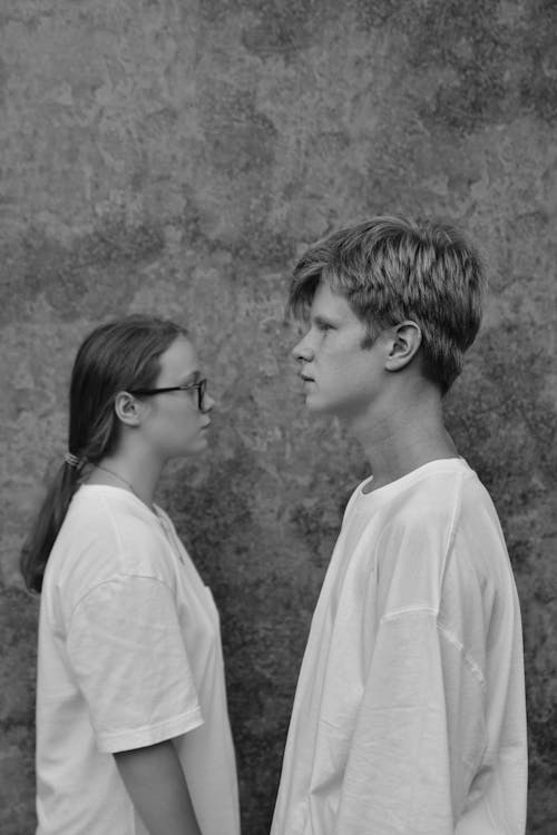 Man and Woman Wearing White T-shirts Standing Near a Wall