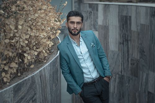 Free Stylish man in a blue suit poses outdoors against a modern wall in Mashhad, Iran. Stock Photo