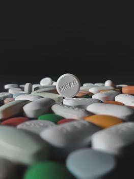 A dramatic close-up of assorted pills and tablets with one prominently labeled 'MICRO.'