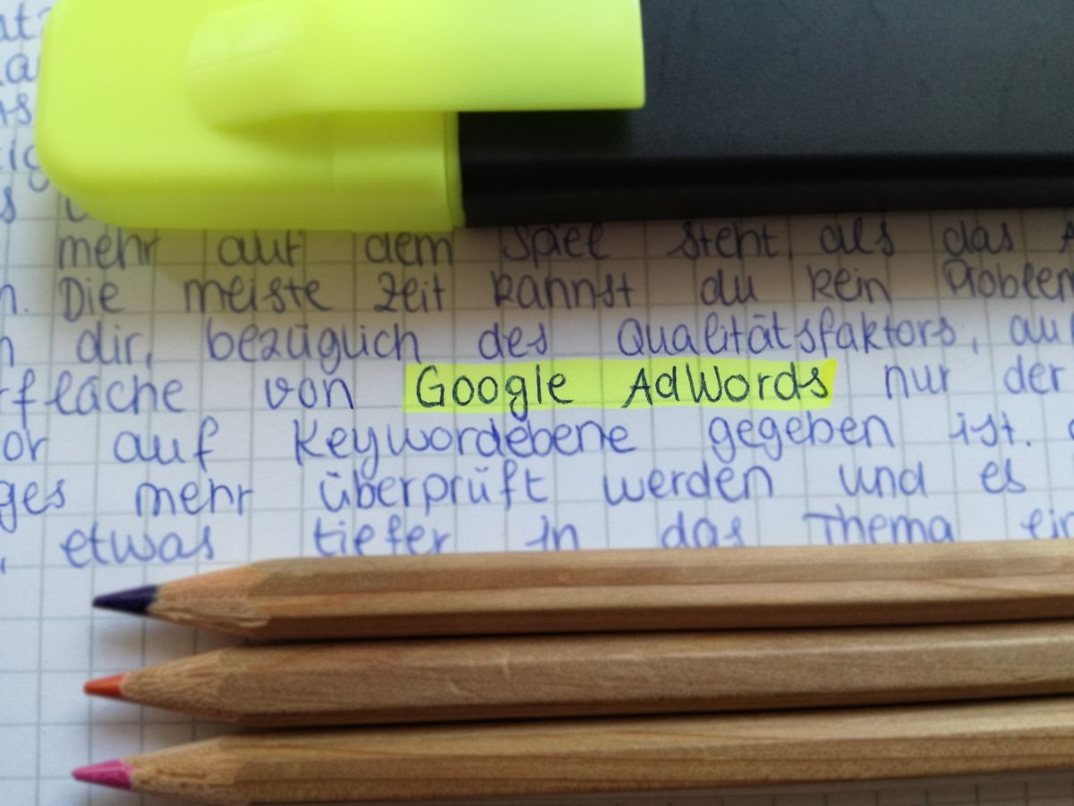Caiet cu notițe scrise de mână despre Google AdWords, alături de creioane colorate