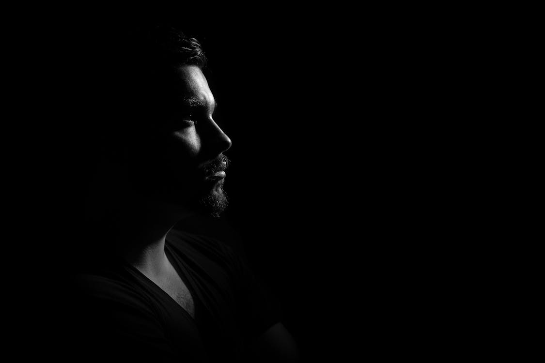 бесплатная фотография человека в черной рубашке с V образным вырезом и черным фоном в оттенках серого Стоковое фото