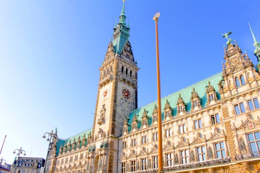 Architectural view of Hamburg City Hall clock tower under a clear blue sky.