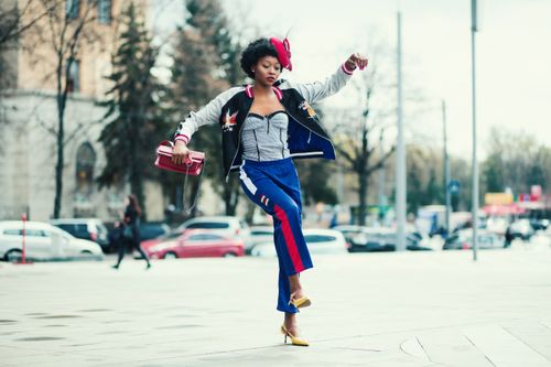 Free Fashionable African woman in vibrant attire jumps on a lively street in Kharkiv. Stock Photo
