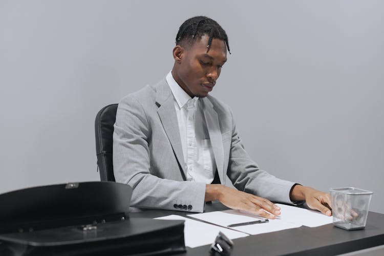 A Man In Gray Suit Looking At The Table With Papers