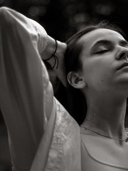 A tranquil black and white portrait of a young woman with eyes closed, evoking calmness.