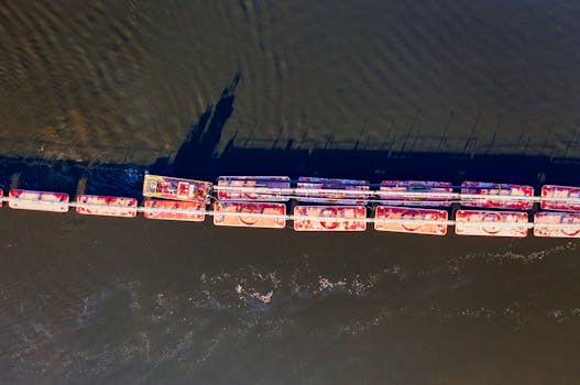 Drone shot of barge line and tugboat navigating river waters, showcasing transportation dynamics.