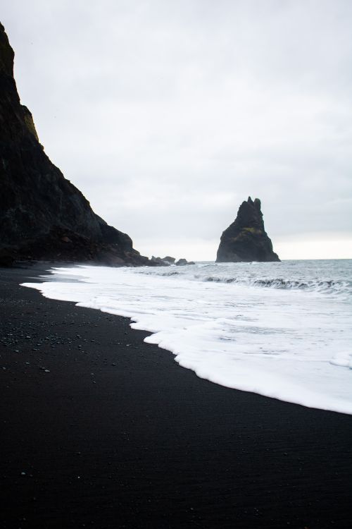 Free Explore the eerie beauty of Iceland's Vik beach with its striking black sand and towering rock formations. Stock Photo