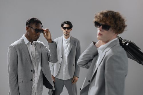 Free Three stylish men in gray suits and sunglasses exuding professionalism and modern corporate style. Stock Photo