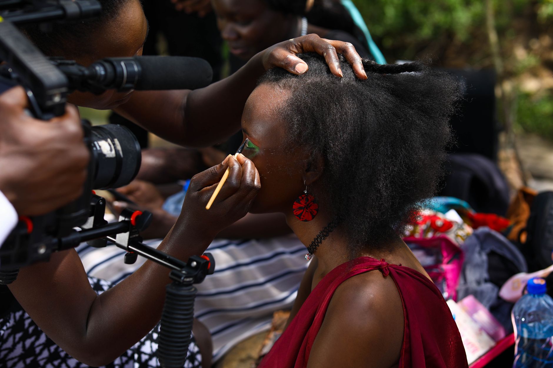 Makeup artist applying makeup to a model during a film shoot, capturing the creative process.