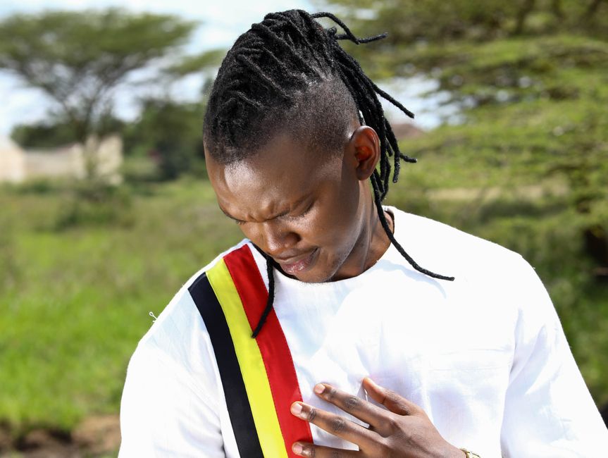 Man in outdoor setting wearing a shirt with national colors, touching his heart with respect.