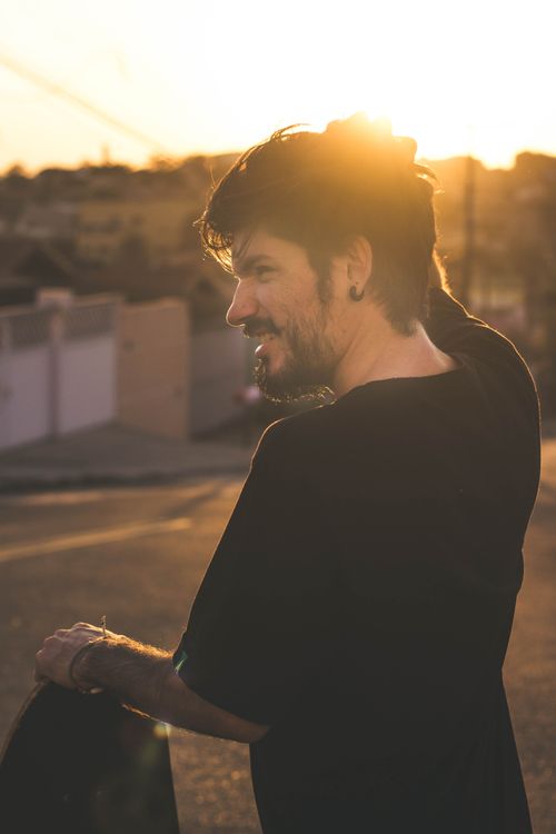 Free A man smiling outdoors during golden hour, capturing a warm and serene moment. Stock Photo