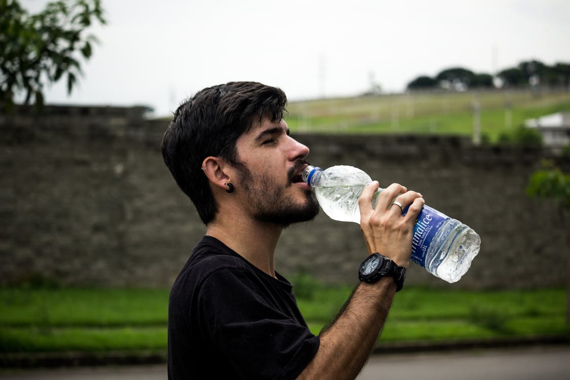 黒のシャツを着て水を飲む男