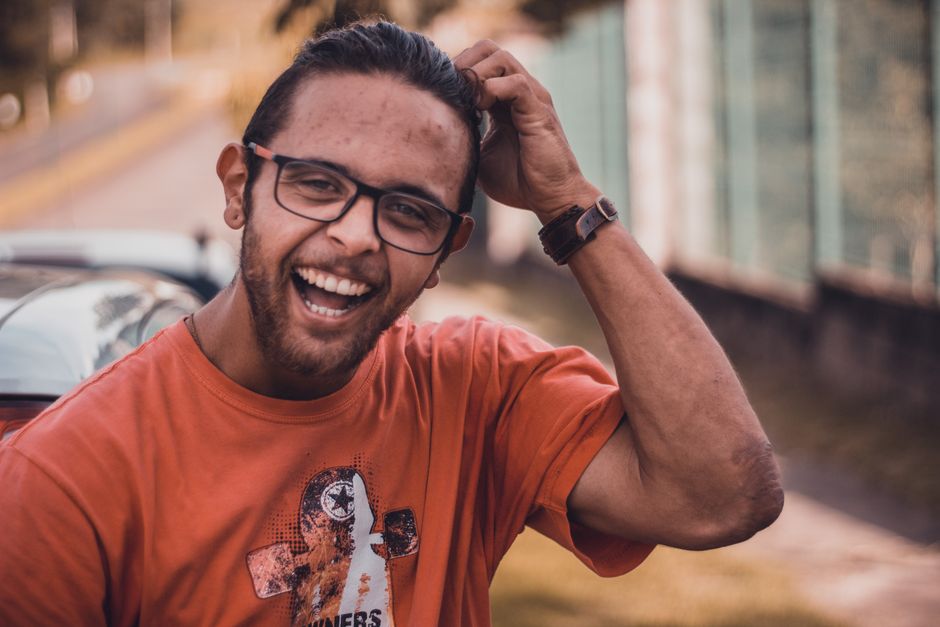 A joyful man wearing glasses smiles in an urban outdoor setting, exuding positivity and style. A joyful man wearing glasses smiles in an urban outdoor setting, exuding positivity and style.