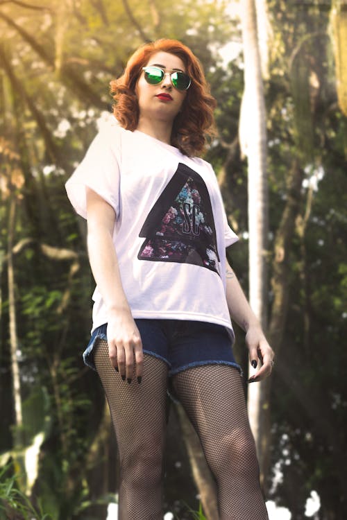 Low Angle Photo of Woman Near Tall Trees during Crepuscular Rays