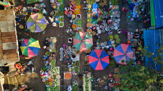 Colorful aerial view of a bustling street market in Mandalay, Myanmar, with diverse vendors and vibrant umbrellas.
