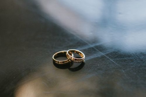 Free Close-up of two elegant gold wedding rings with diamonds on a reflective surface. Stock Photo