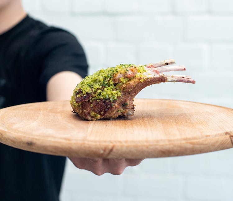 Man Holding Meat On Cutting Board