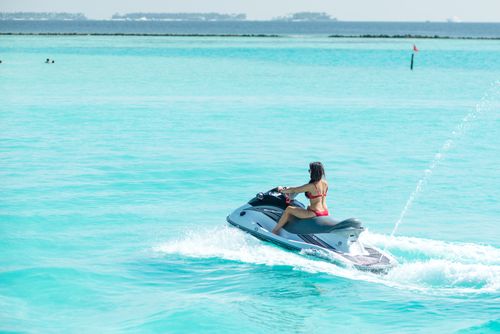 Free A woman in a bikini rides a jet ski in the turquoise waters of the Maldives, enjoying a sunny day. Stock Photo