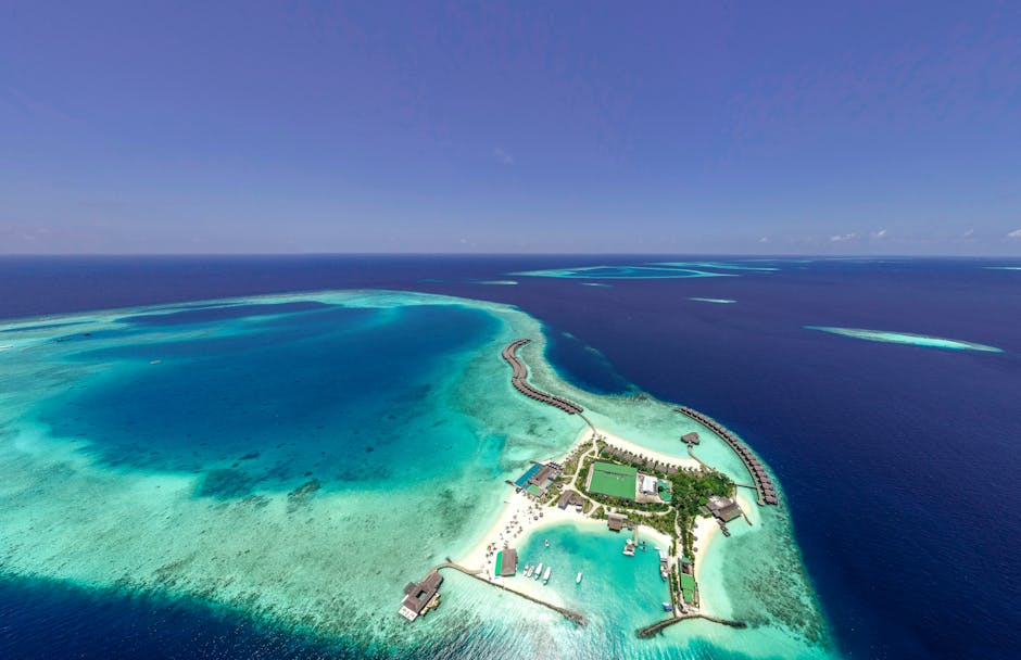 Explore this breathtaking aerial view of a luxury island resort in the Maldives, with crystal-clear waters and vibrant coral reefs.
