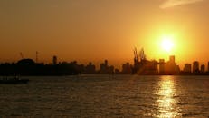 城市天际线上令人惊叹的日落倒映在港口水域，轮廓和起重机清晰可见