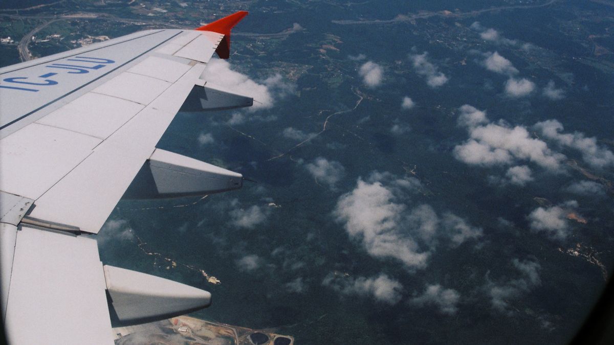 View from airplane window showing clouds and landscape below. Ideal travel-themed image.