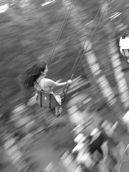 Grayscale Photo of a Woman Sitting on Swing
