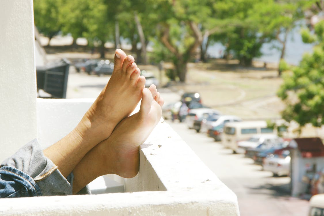 Person Wearing Blue Denim Jeans With Feet on Railings