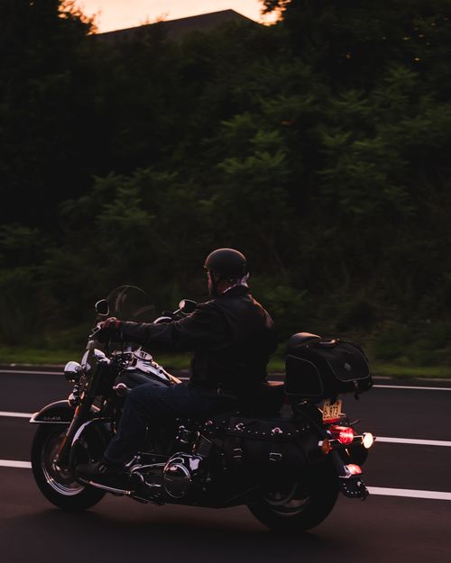 Free A motorcyclist rides on a rural road during twilight, showcasing freedom and adventure. Stock Photo