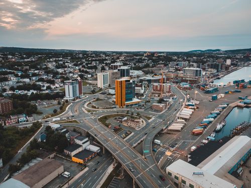 Free Dynamic aerial view of a cityscape featuring highways, buildings, and waterfront at sunset. Stock Photo