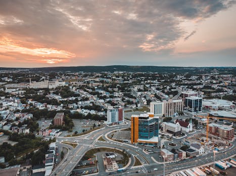 Drone shot capturing cityscape at sunset with a vibrant sky over a bustling urban area.