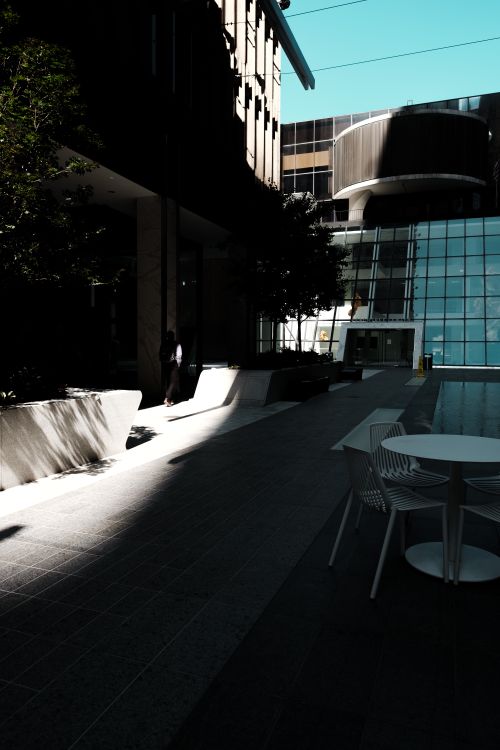 Free Modern outdoor seating area with tables and chairs in an urban setting, featuring dramatic lighting and architecture. Stock Photo