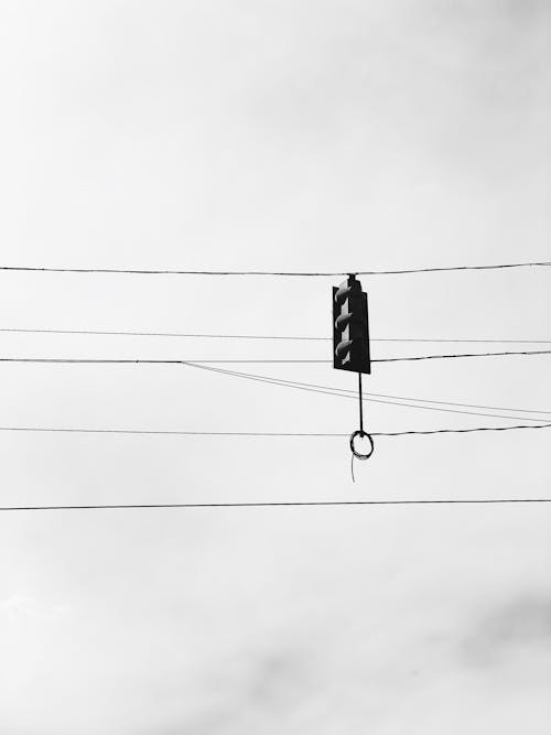 Monochrome Photo of a Traffic Light Hanging on Cables