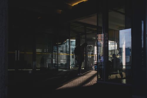 Free Dramatic silhouettes of people inside a modern glass building at dusk. Stock Photo
