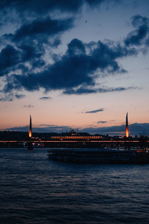 Free A scenic twilight view of the illuminated Galata Bridge over the Bosphorus with a dramatic sky. Stock Photo