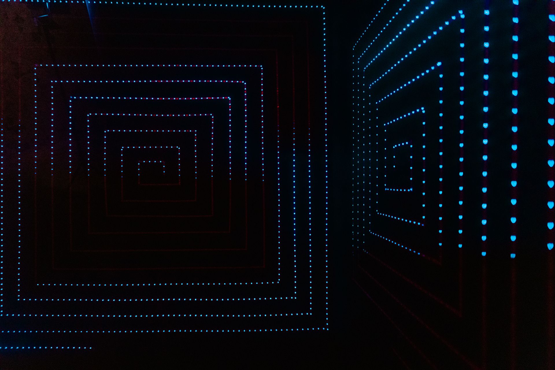 Abstract LED light pattern creating a geometrical illusion in a dark room setting.