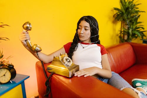 Woman in Red and White Shirt Holding Golden Telephone
