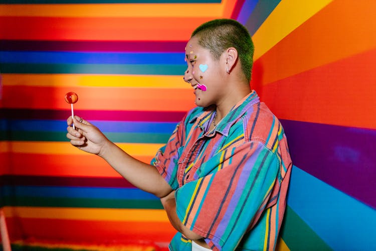 Man In Red And Green Stripe Shirt Holding Red Lollipop