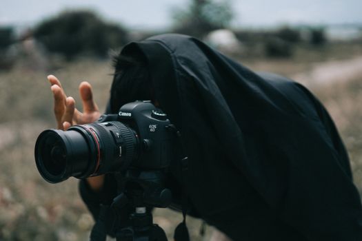 Person using a professional camera outdoors, capturing nature scenes.